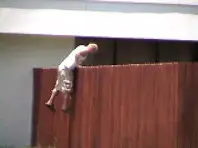 A man climbing over the top of a fence.